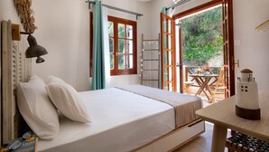 Une chambre à coucher comprenant un lit, un bureau et un balcon avec une table et des chaises.