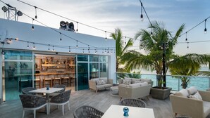 An outdoor patio area with wicker furniture, a bar with glass doors, and a view of the ocean.