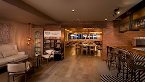A cozy lounge area with a sofa, chairs, and a bar with stools. A kitchen area is visible in the background.