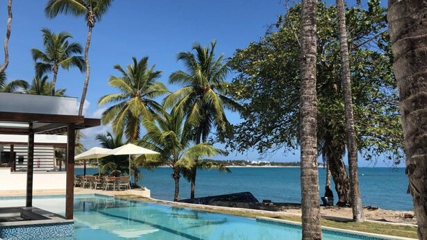 A pool area with lounge chairs, palm trees, and a view of the ocean. - 1 Bedroom Garden View Presidential Suites Cabarete (Sosúa)