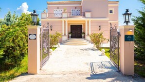A villa with a central entrance, a gated driveway, and a well-maintained garden. - Villa Denise in Corfu (Corfu)