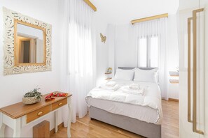 Une chambre à coucher avec un lit, une table de chevet, un miroir et une fenêtre avec des rideaux.