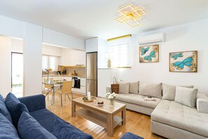 Ein modernes Wohnzimmer mit Sofa, Couchtisch und einer Küche im Hintergrund.