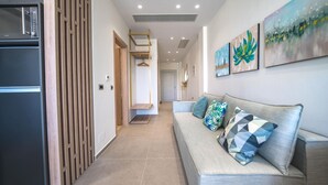 A modern hallway with a sofa, artwork, and a refrigerator.