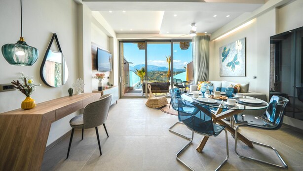 A modern dining area with a glass table and chairs, a wooden counter, and a view of the outdoors.