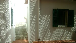 A staircase with a wooden bench, white walls, and a window with green shutters.