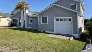 A two-story house with a garage, a small front porch, and a palm tree.
