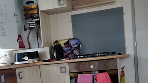 Una cocina compacta con estufa a gas, microondas y refrigerador pequeño. Cuenta con encimera de madera y lavamanos.
