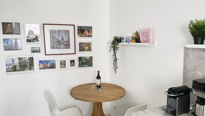 A modern kitchen with a round wooden table, white chairs, a coffee machine, and a wine bottle. - Charming & central living in Weiden - Hej (Weiden in der Oberpfalz)