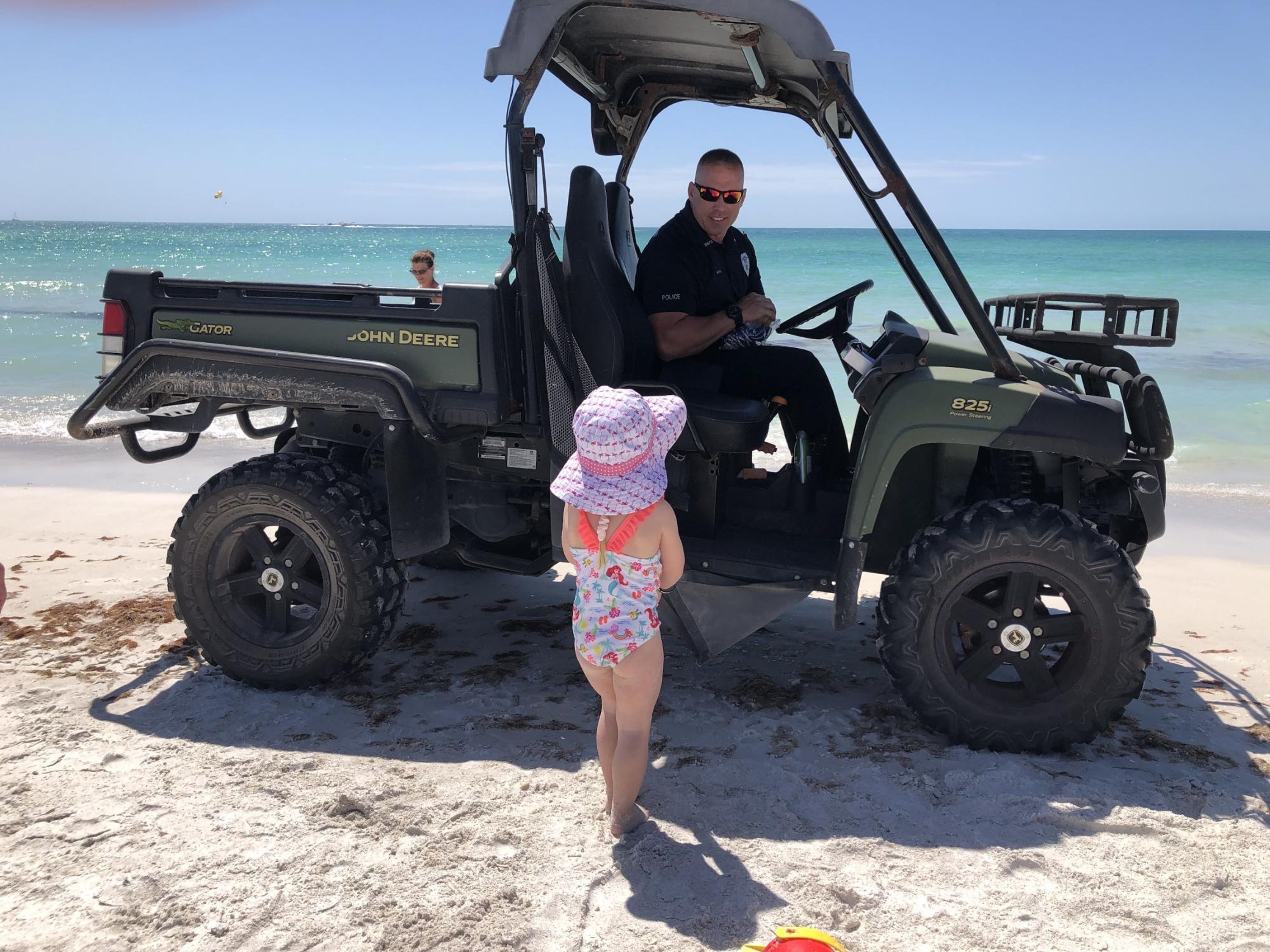 A beach scene with a police vehicle and a child.