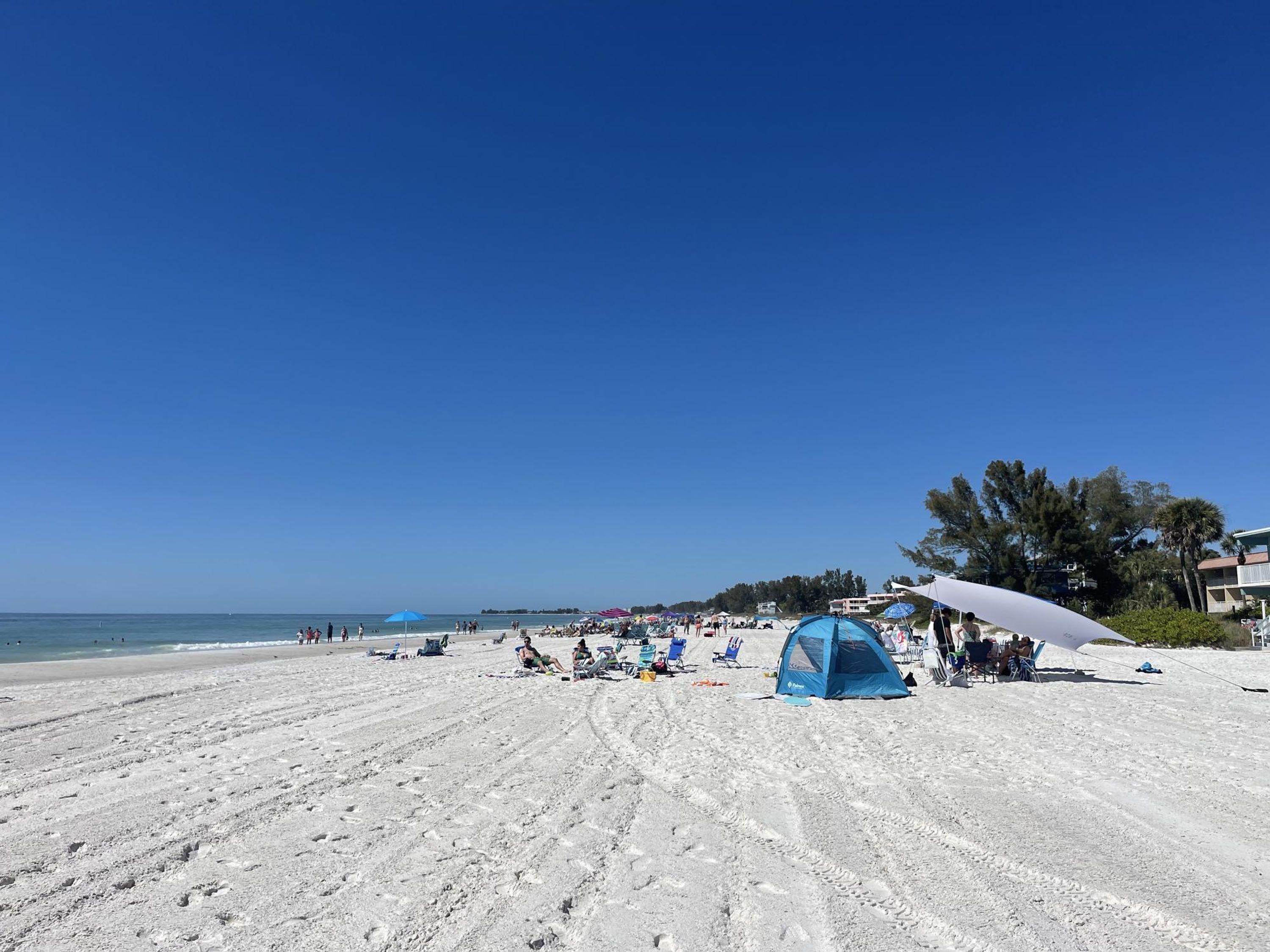 Una spiaggia con una tenda, ombrelloni e lettini.