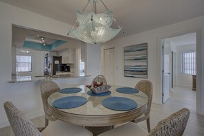 Enjoy meals in this stylish dining area with a round table, wicker chairs, and a unique chandelier.