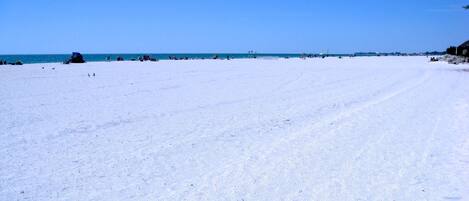 Een breed, open strand met een heldere lucht en rustige zee.
