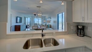 A modern kitchen with a large island, stainless steel sink, and pendant lighting. - Anna Maria Island Beach Sands (Bradenton Beach)