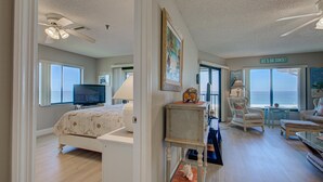 A spacious room with a bed, a television, a desk, and a view of the ocean. - Anna Maria Island Beach Sands 201 (Bradenton Beach)