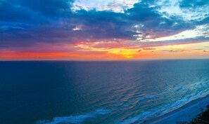 Vista de un atardecer costero con playa y océano.