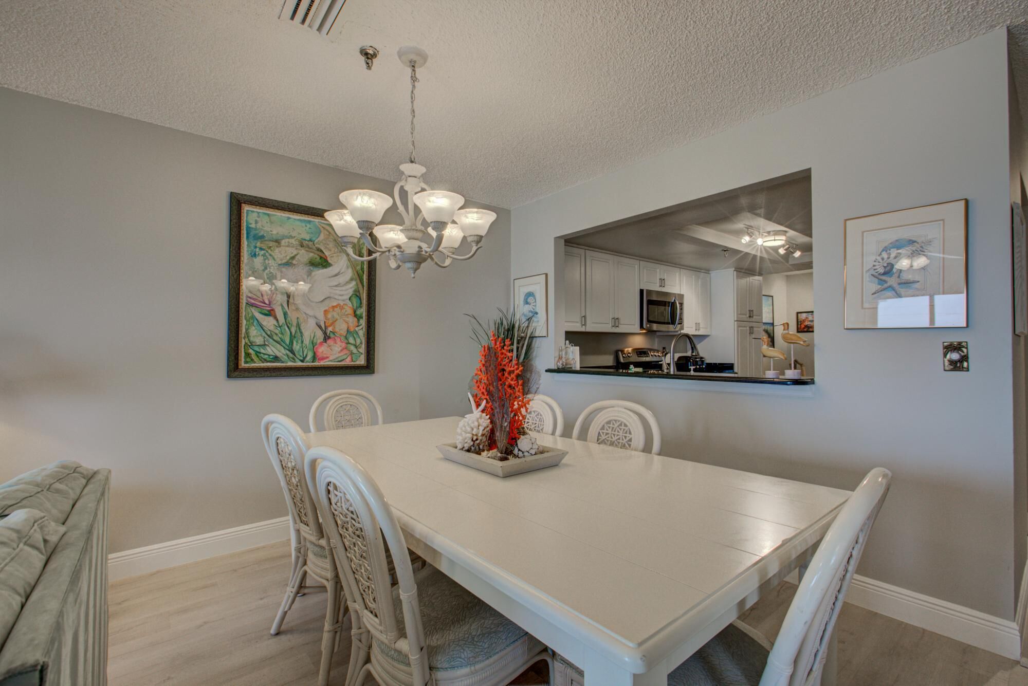 A dining area with a white table and chairs, a chandelier, and artwork on the walls.