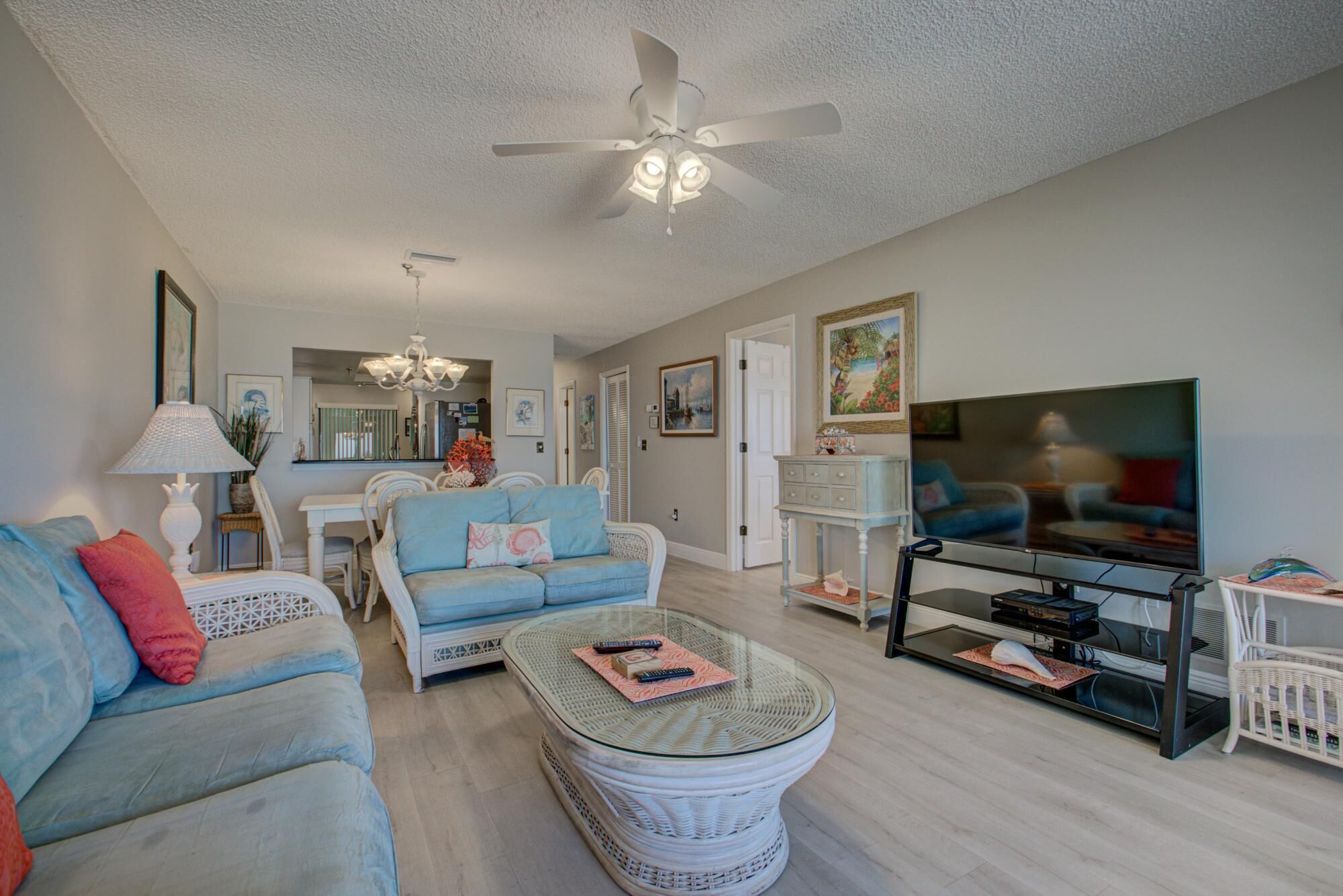A living room with a sofa, coffee table, TV, and ceiling fan.