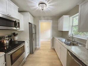 A modern kitchen with stainless steel appliances, a granite countertop, and a view to the dining area.