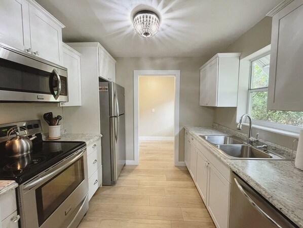 A modern kitchen with stainless steel appliances, a granite countertop, and a view to the dining area.