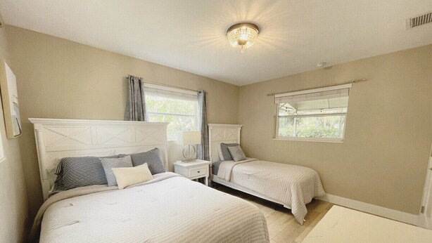 A bedroom with two beds, a nightstand, a lamp, and a ceiling light fixture. - Recently Updated 2/2 With Hot Tub, 1 Mile to Beach (Lantana)