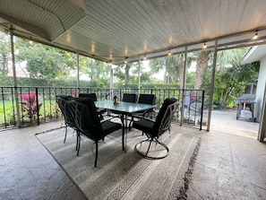 A covered patio area with a table and chairs, surrounded by glass railings and greenery. - Recently Updated 2/2 With Hot Tub, 1 Mile to Beach (Lantana)