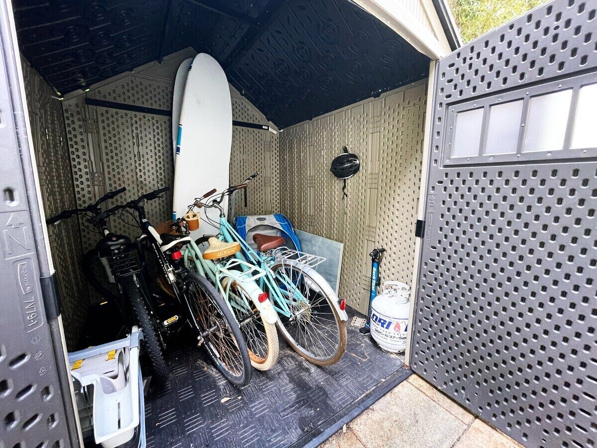Un garage où sont rangés des vélos et une planche de surf.