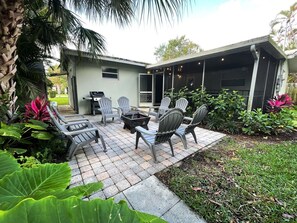 An outdoor patio area with a fire pit, seating, and a covered section.