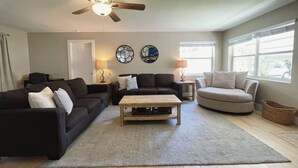 A living room with a ceiling fan, two couches, a coffee table, and a window with blinds. - Recently Updated 2/2 With Hot Tub, 1 Mile to Beach (Lantana)