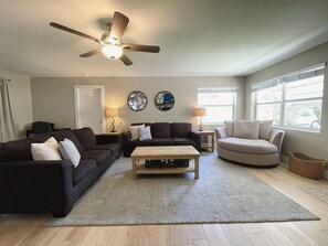A living room with a ceiling fan, two couches, a coffee table, and a window with blinds. - Recently Updated 2/2 With Hot Tub, 1 Mile to Beach (Lantana)
