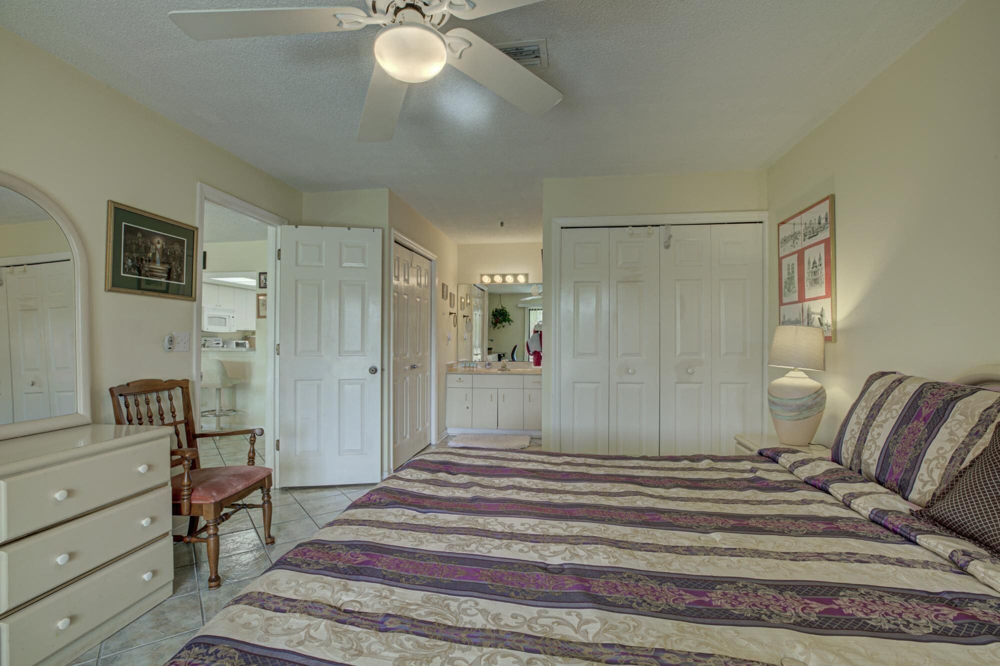 A bedroom with a bed, a dresser, a chair, and a ceiling fan.