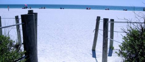 A sandy beach with a wooden fence leading to the water.