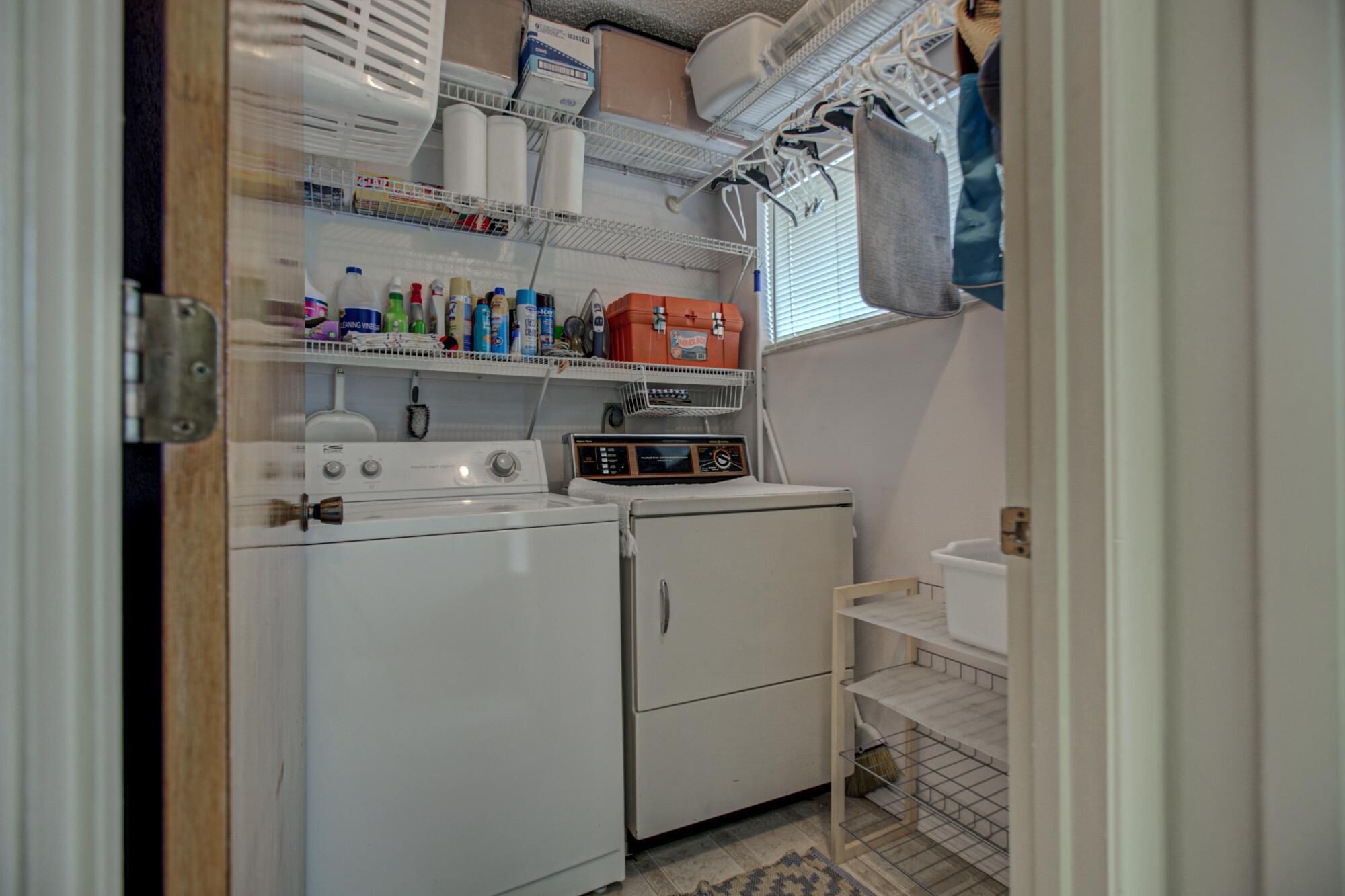 A laundry room with a washing machine, dryer, and shelves with cleaning supplies.