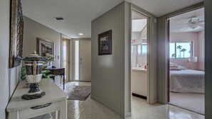 A hallway leading to a bedroom with a bed, a bathroom, and a dining area with a table and chairs. - Anna Maria Island Bridge Port Beach Resort (Bradenton Beach)
