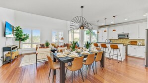 A modern kitchen with white cabinets, a central island, and a dining area with a table set for six.