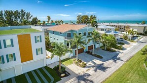 A coastal residential area with modern houses, a clear view of the ocean, and a well-maintained lawn.