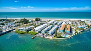 Luchtbeeld van een kusthotel met meerdere gebouwen, een parkeerplaats en een strand op de achtergrond.