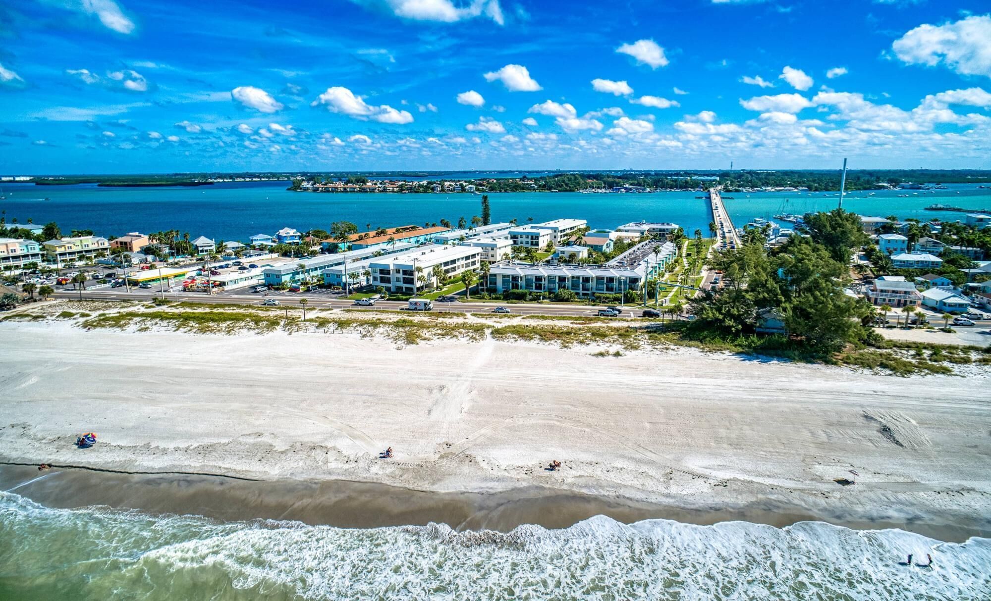 A coastal town with beachfront properties, a marina, and a long pier extending into the water.