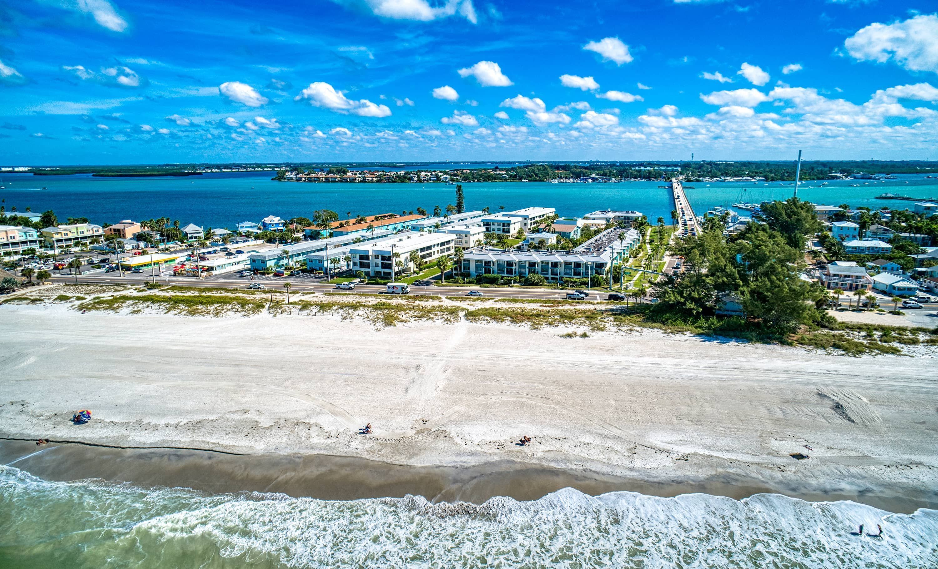 A coastal town with beachfront properties, a pier, and a clear view of the ocean.
