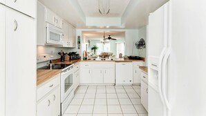 Een moderne keuken met witte kasten, een houten aanrecht en een centraal eiland.