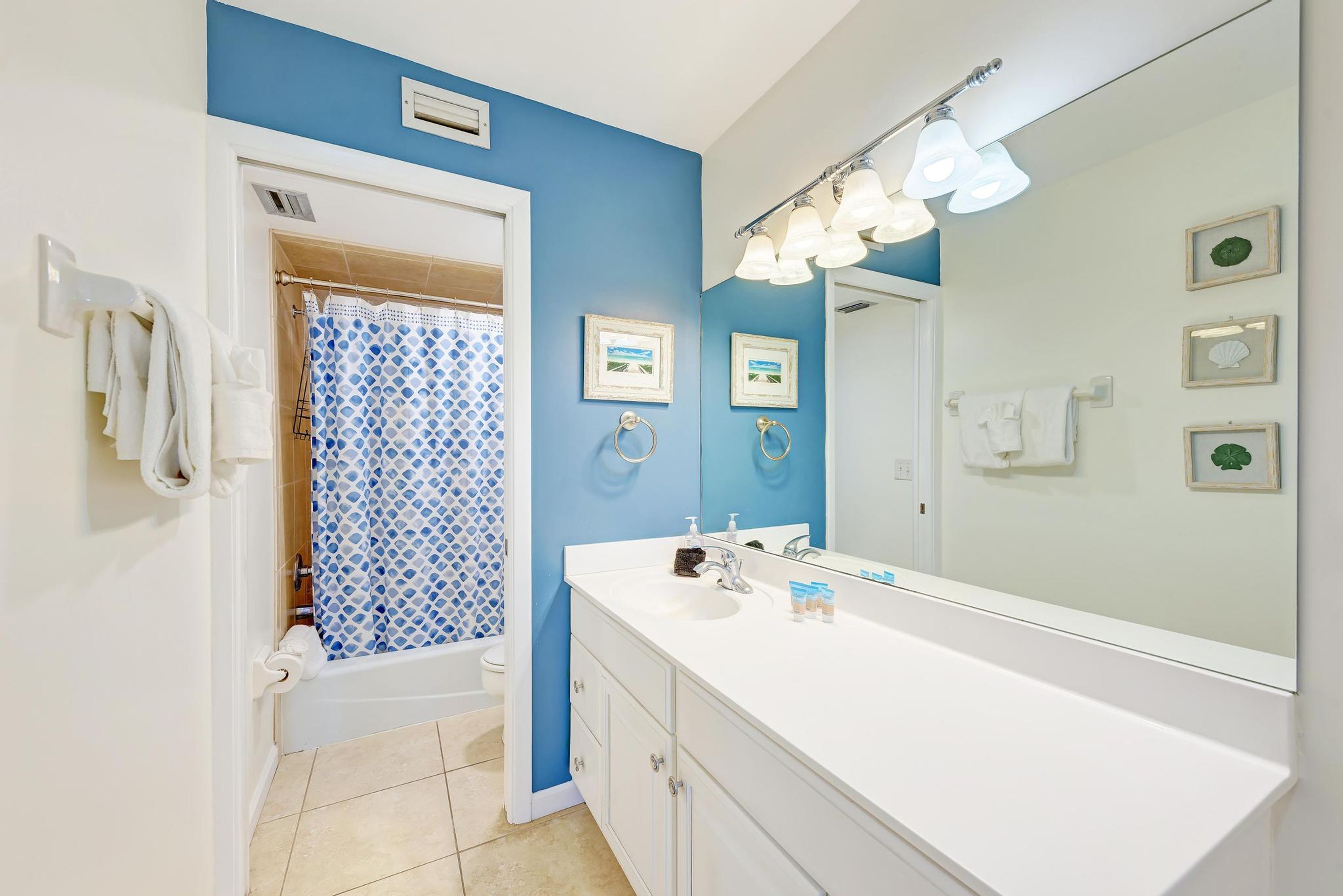 Een badkamer met een blauwe wand, een wit wastafelmeubel en een douchegordijn.