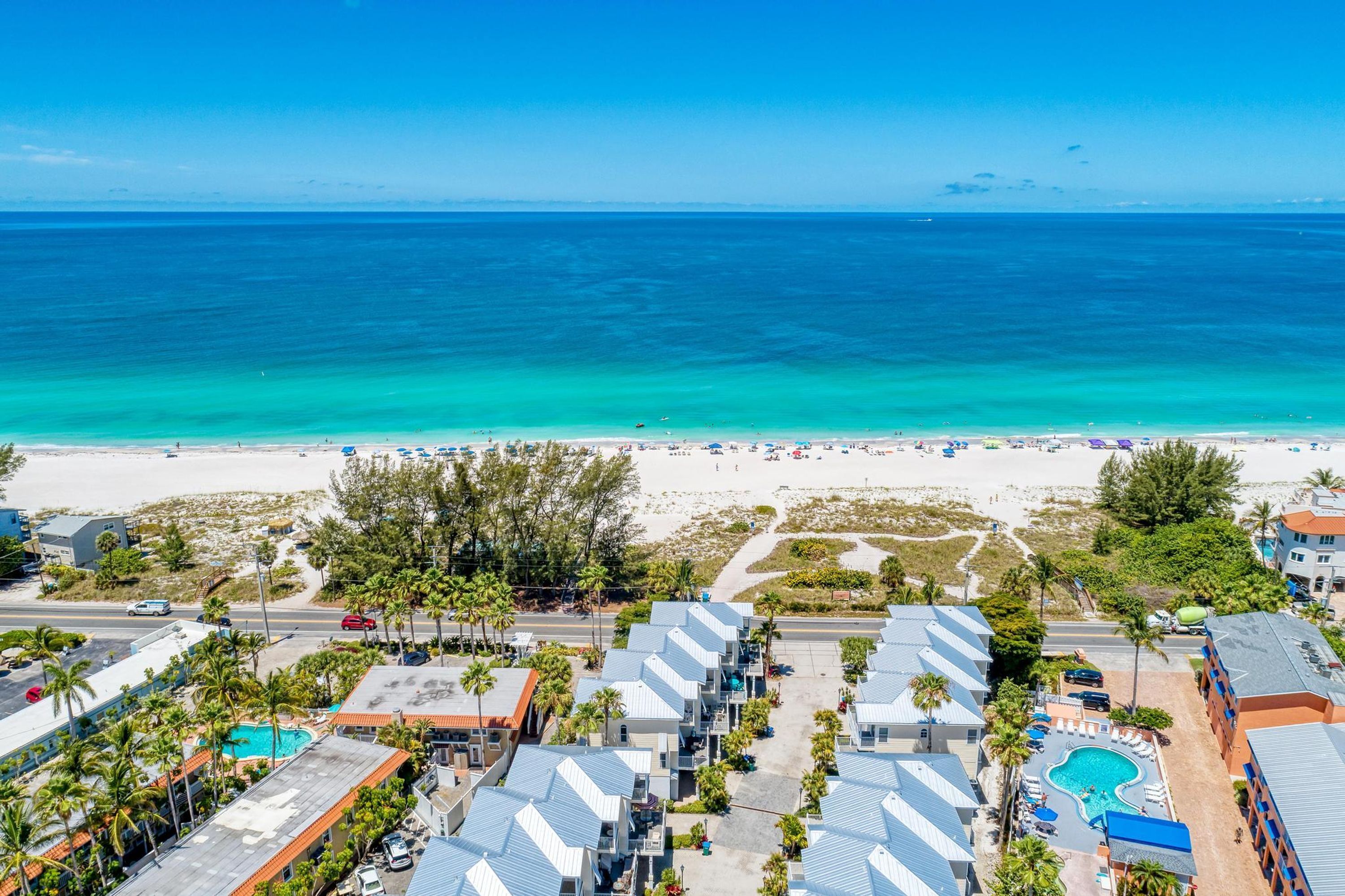A beachfront hotel with multiple-story buildings, a swimming pool, and a beach view.