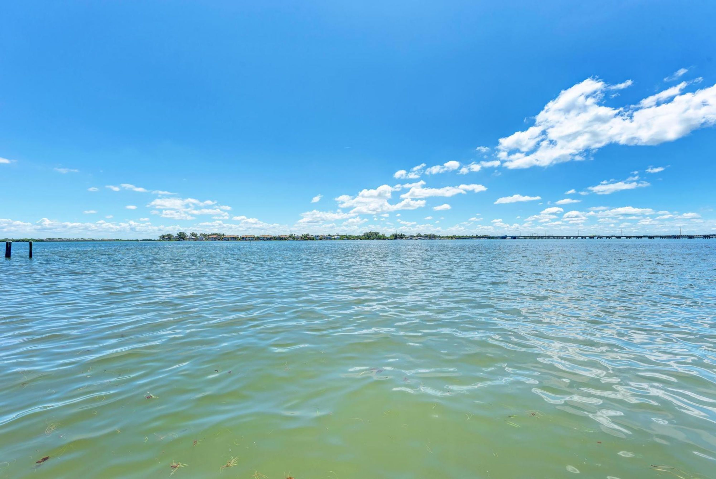 Une étendue d'eau calme, sous un ciel dégagé, avec une terre lointaine à l'horizon.