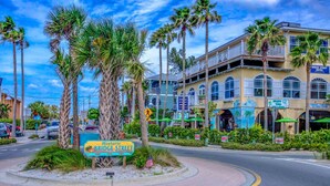 A street corner with a sign for Historic Bridge Street, surrounded by palm trees and buildings with balconies. - Anna Maria Island Beach Palms 2A (Bradenton Beach)