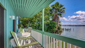 A covered porch with outdoor seating, a view of a lake, and a palm tree. - Anna Maria Island Beach Palms 2A (Bradenton Beach)