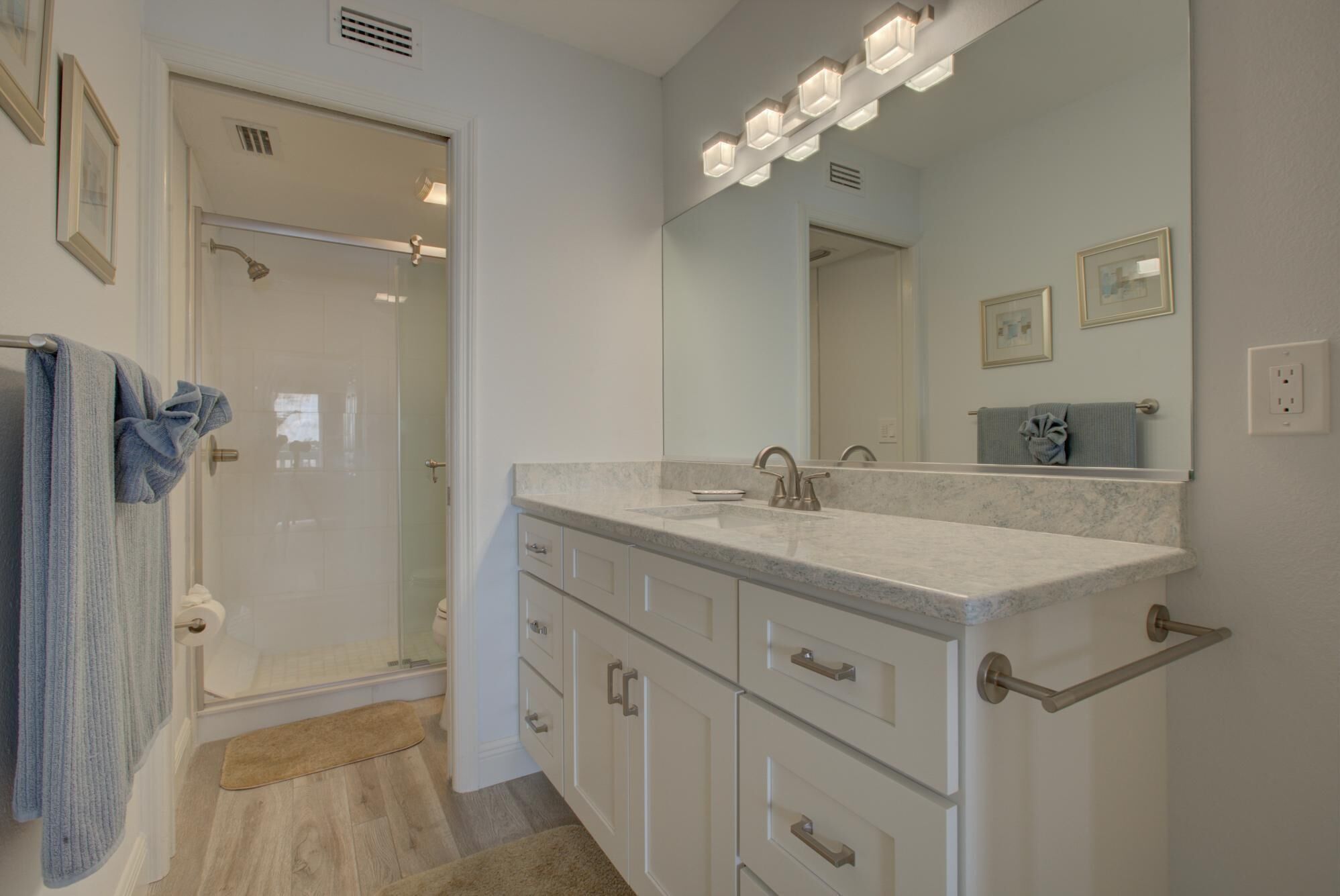 A modern bathroom with a shower, a sink, and a vanity with drawers.