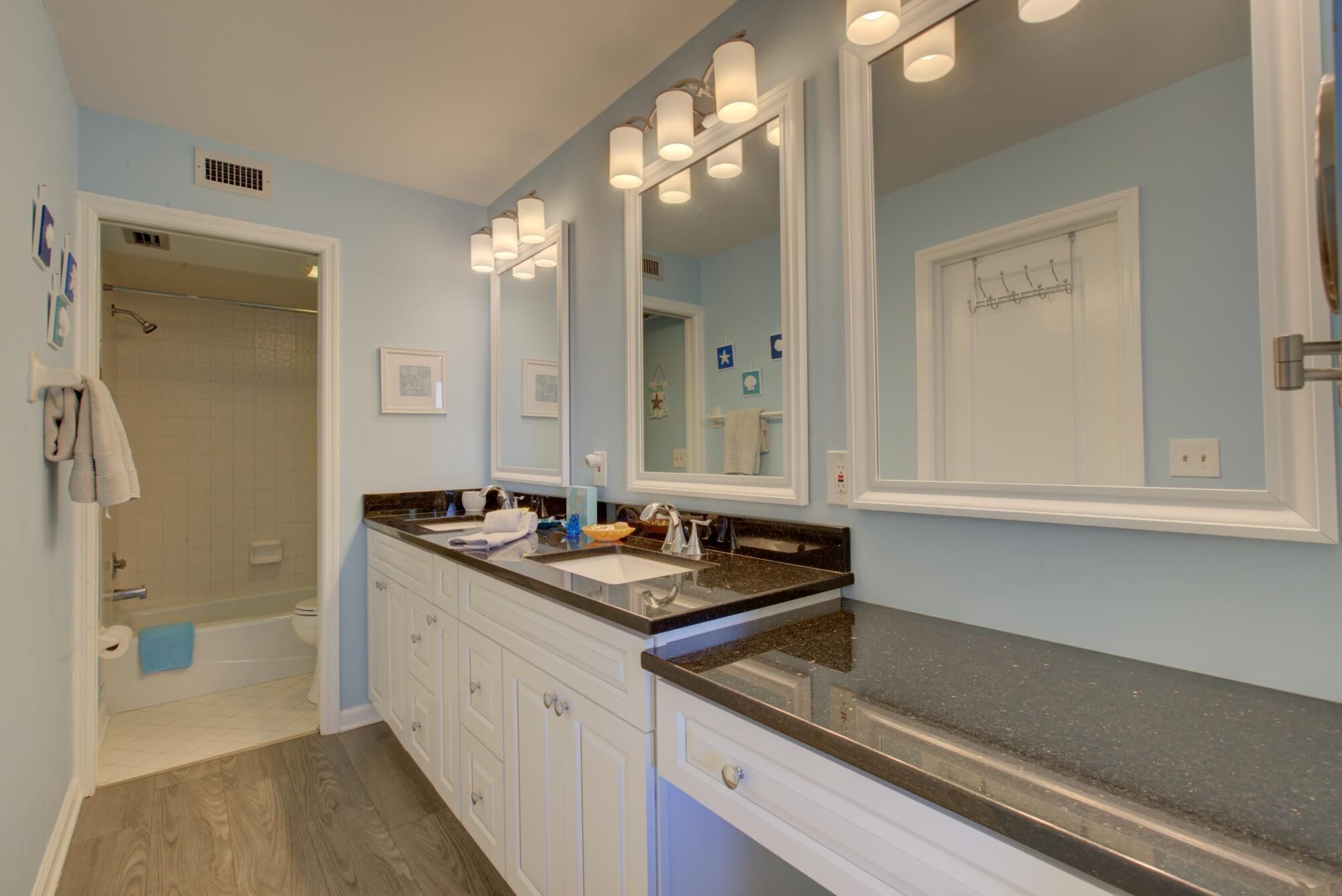 A bathroom with a double vanity, a shower, and a walk-in closet.