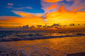 Un coucher de soleil sur l’océan, les vagues reflétant les couleurs du ciel.