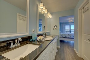Une salle de bain dotée d’un grand miroir, de deux lavabos et d’un meuble-lavabo avec des tiroirs.