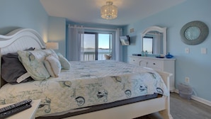 A bedroom with a bed, a dresser, a television, and a balcony with a view. - Anna Maria Island Retreat (Bradenton Beach)